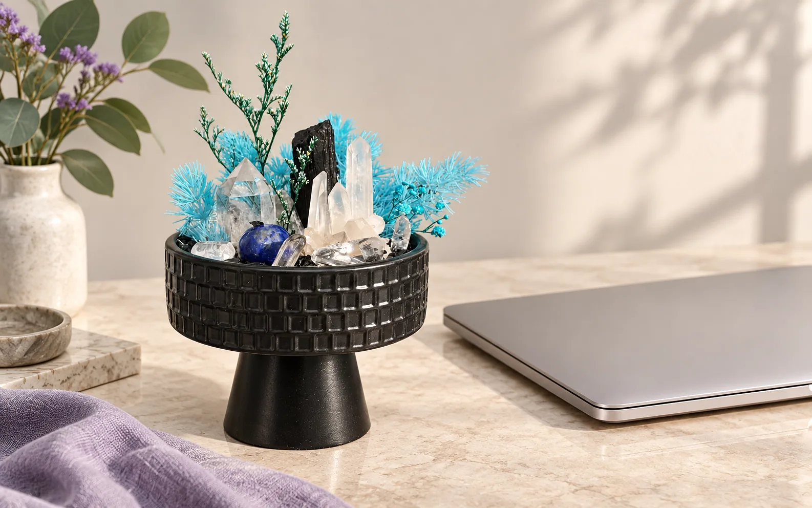 Blue and clear crystal garden beside a closed laptop.
