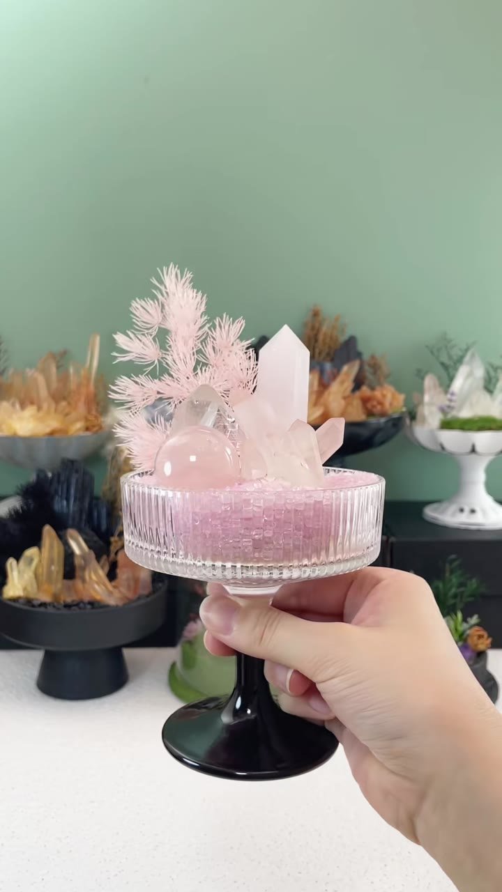 A pink crystal garden held in front of a display of finished arrangements
